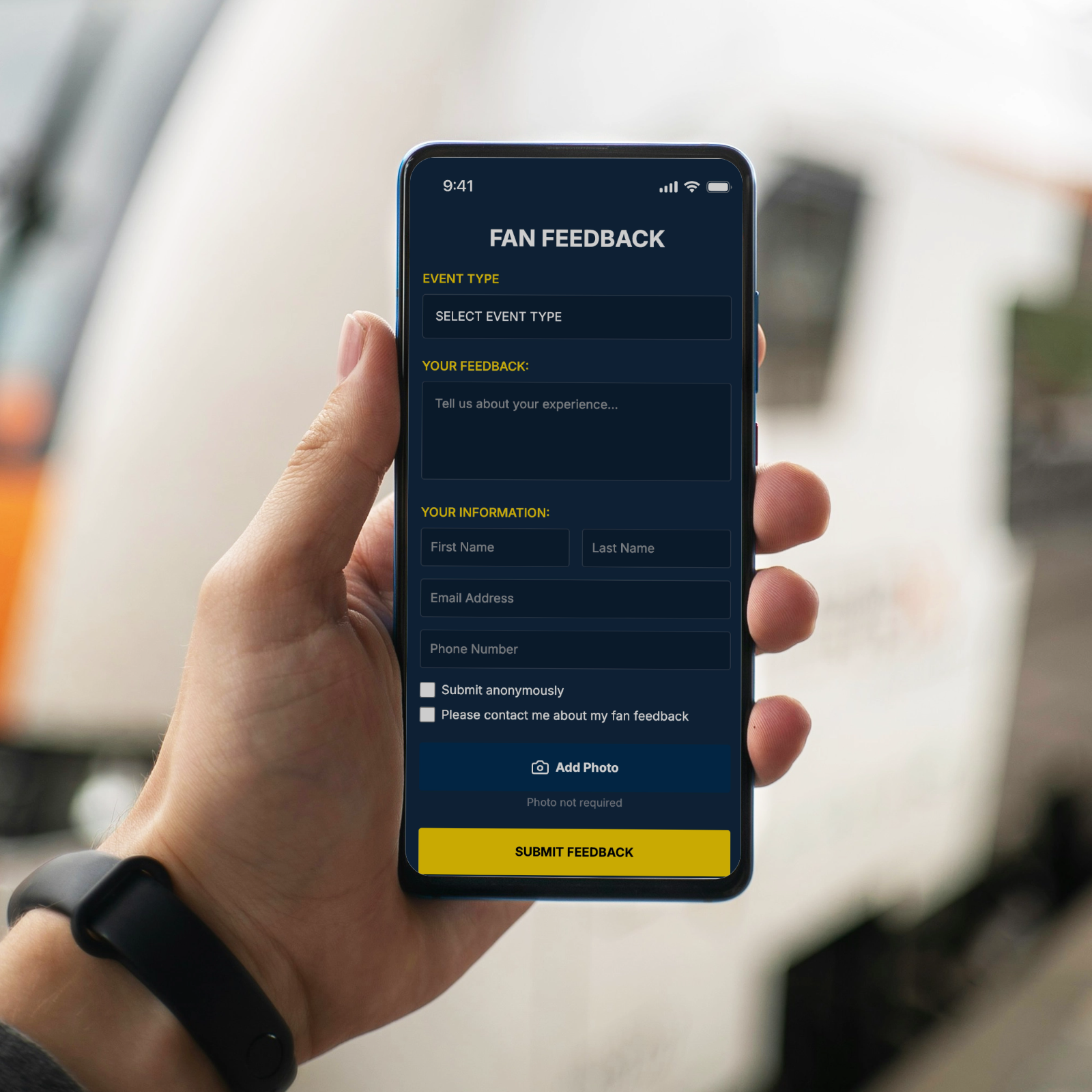 Hand holding mobile phone showing fan feedback form interface