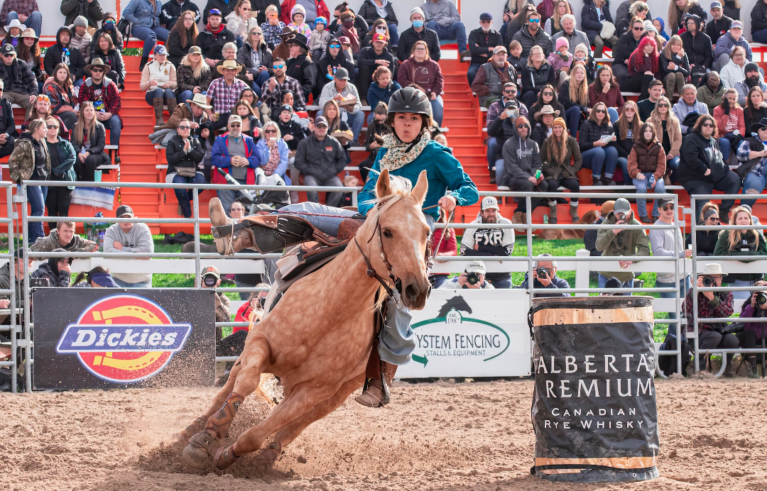 A person on a horse barrel racing at a rodeo.