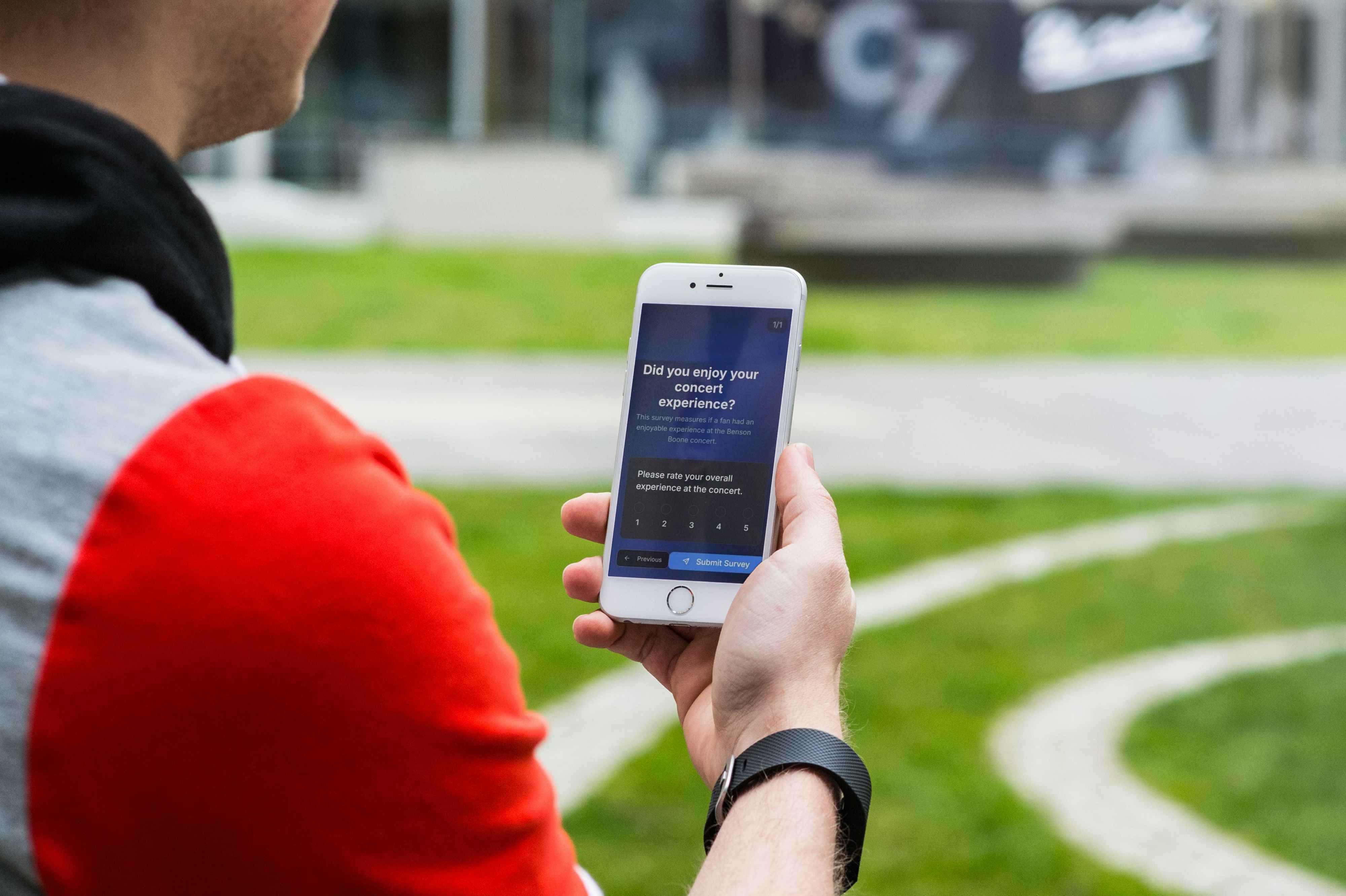 Person holding phone with concert experience survey showing 5-star rating system